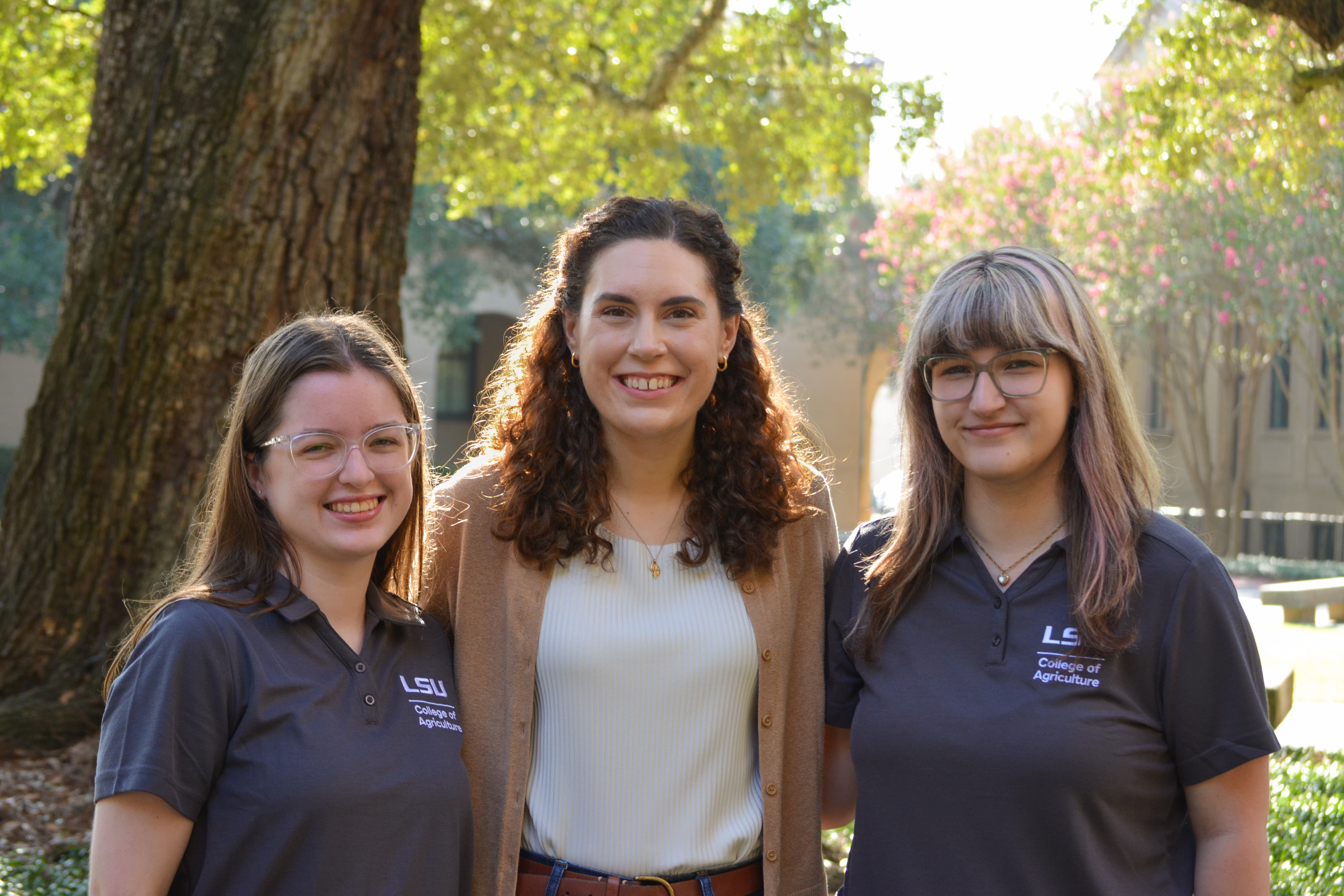 Peer mentor advisor stands with peer mentors Kate Buchholtz and Ava Fontentot