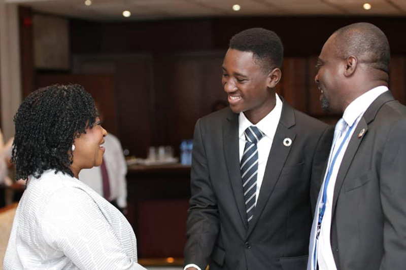 Marcus Ashiangmor shakes hands with a woman in a white suit