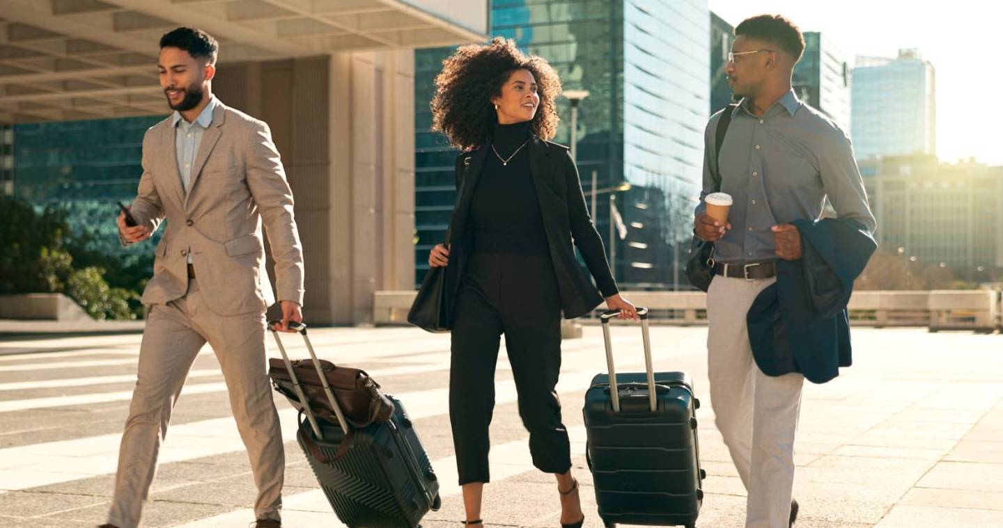 REQUEST A FACULTY TRAVEL GRANT Three professionals with luggage walking and talking