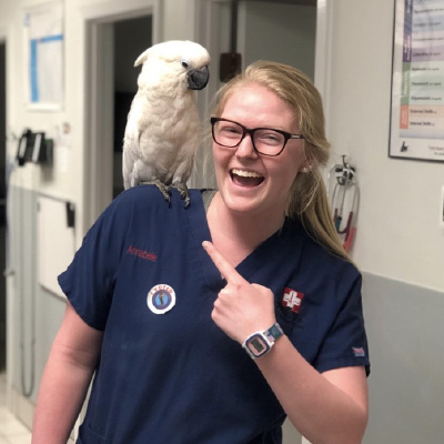 Annabelle points to a cockatoo on her shoulder. 